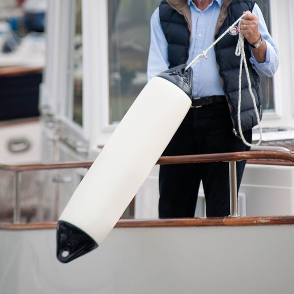 Polyform F2 fender på stranden med båd i baggrunden